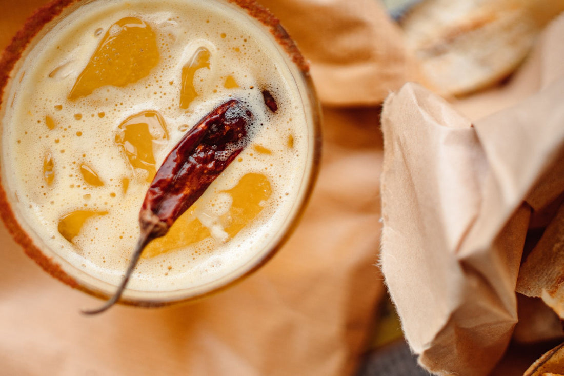 top view of glass of orange spicy cocktail with chilli pepper in it